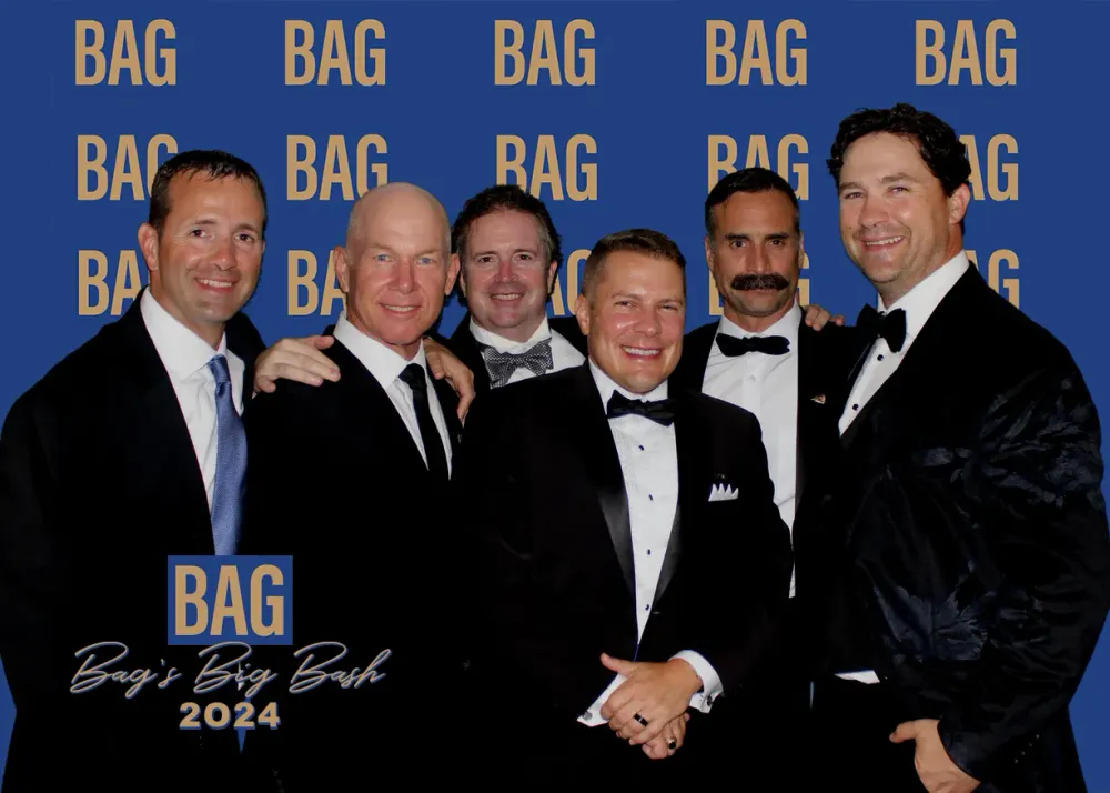 Friends in black tie in front of the Bag's Big Bash backdrop