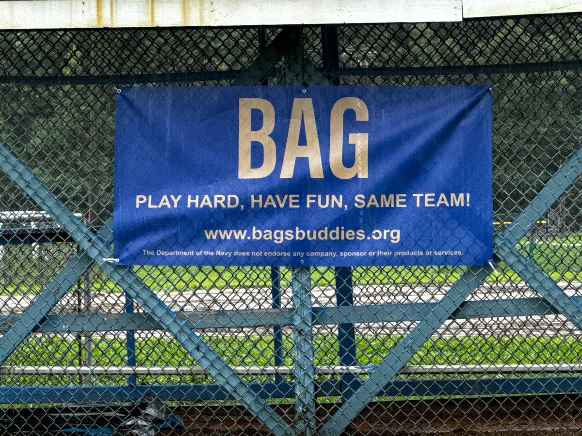 Bag's Buddies banner displayed on a sports field fence